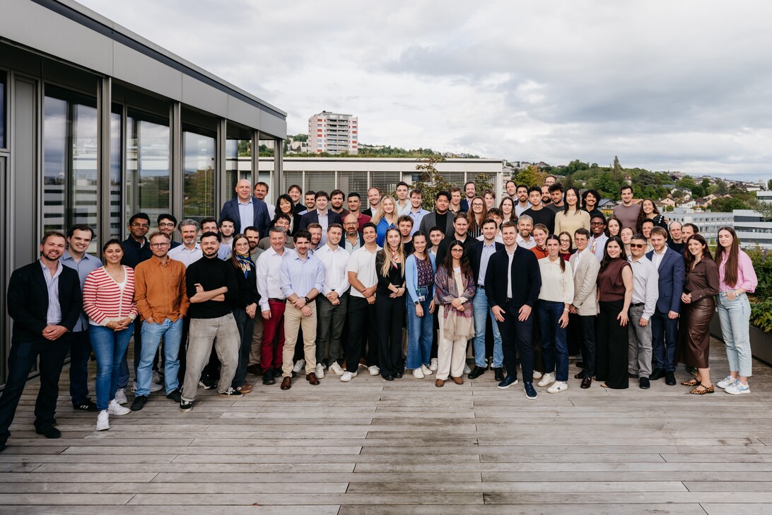 Visium - IP | Realidad Económica Group of diverse professionals posing on a rooftop deck with city buildings in the background.