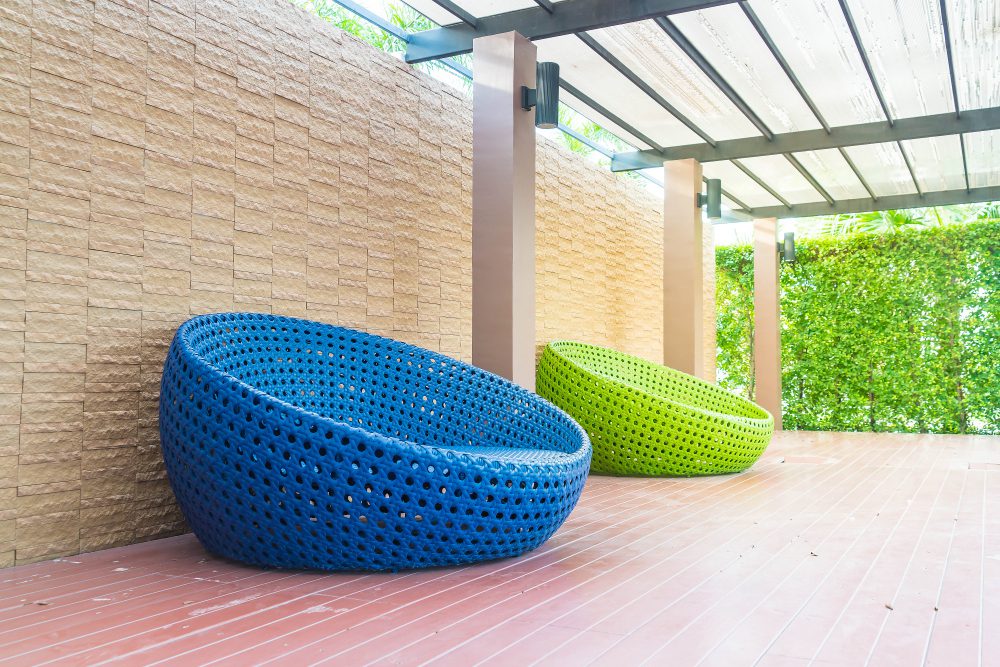 778533 - Toldos Eguzki | Realidad Económica Blue and green circular woven outdoor lounge chairs on a wooden deck under a covered patio. (informative)